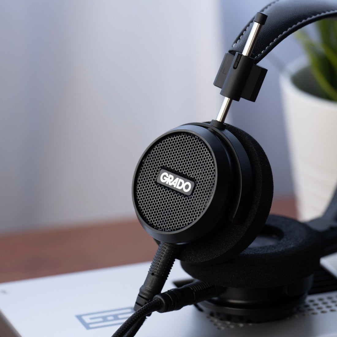 Grado Signature S150 headphones resting on a desktop DAC