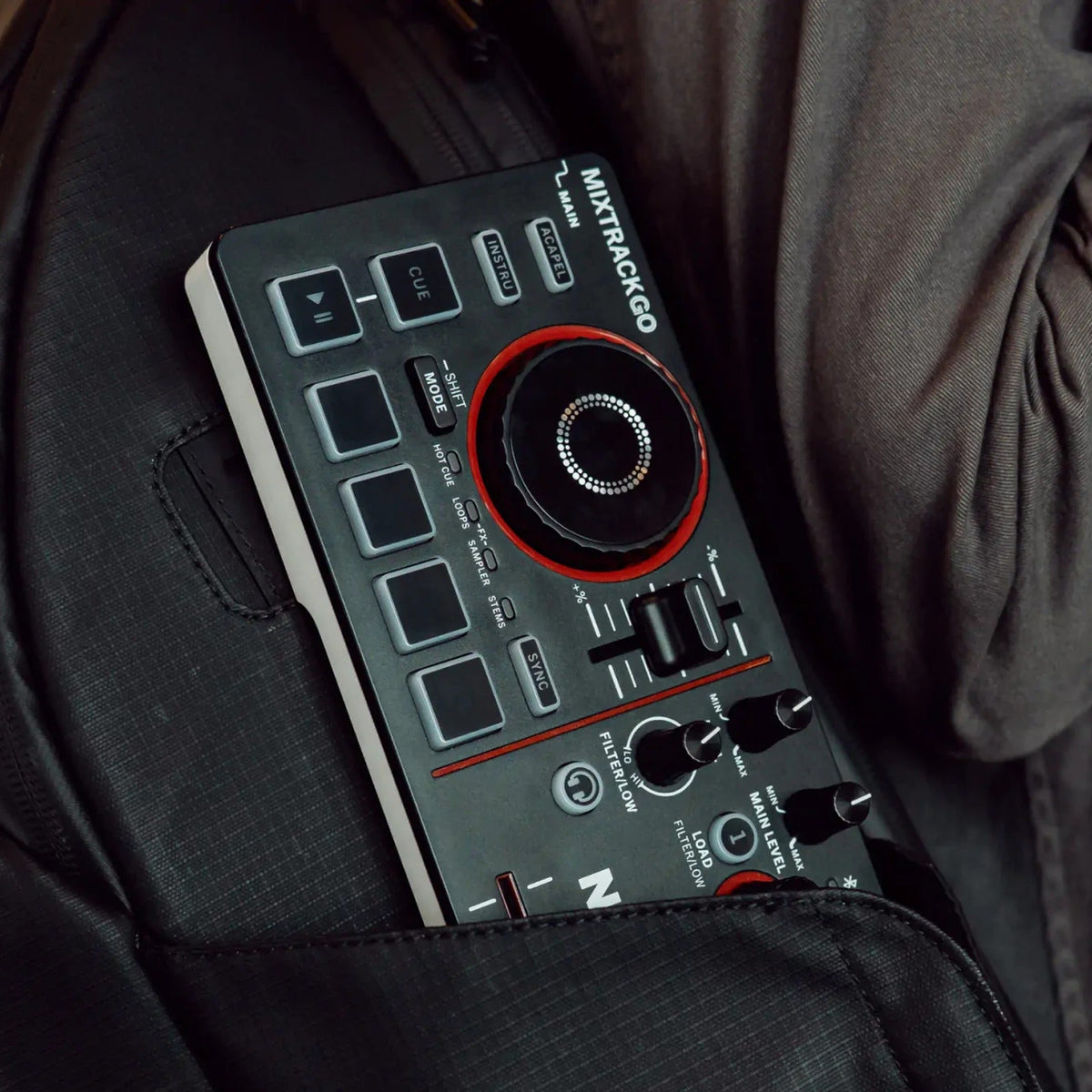 Numark Mixtrack Go tucked into a jacket pocket, showing its ultra-portable size