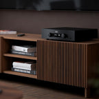 Hegel H200 integrated amplifier on a walnut sideboard in a living room below a wall-mounted TV
