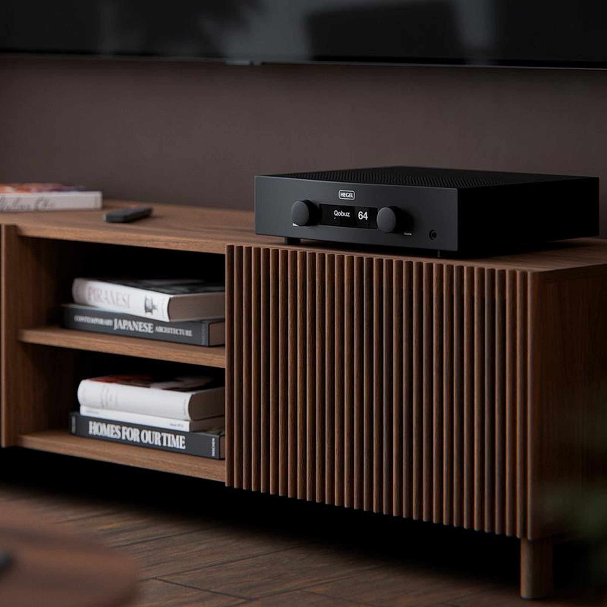 Hegel H200 integrated amplifier on a walnut sideboard in a living room below a wall-mounted TV